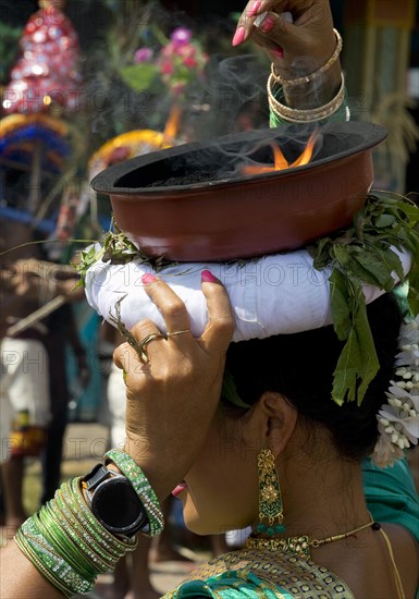 A Hindu woman carries a fire bowl during the big procession Theer