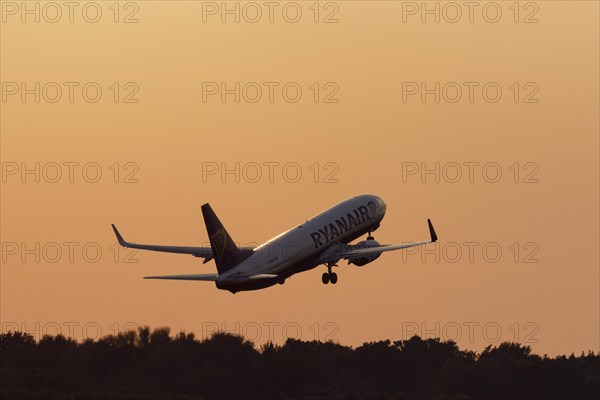 Passenger aircraft Boeing 737-8AS of the airline Ryanair taking off in the evening glow at Hamburg Airport