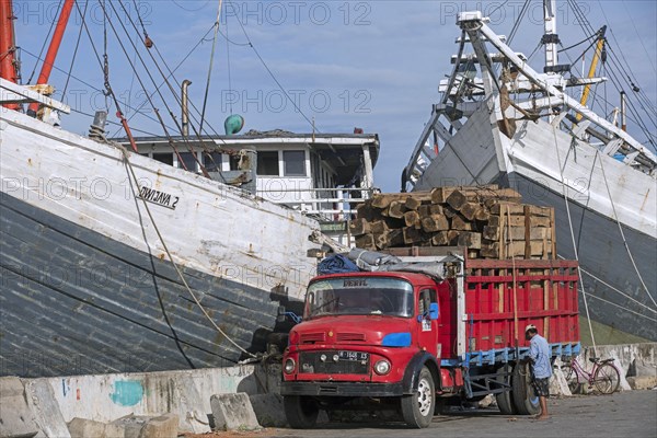 Truck loaded with timber in front of wooden pinisis