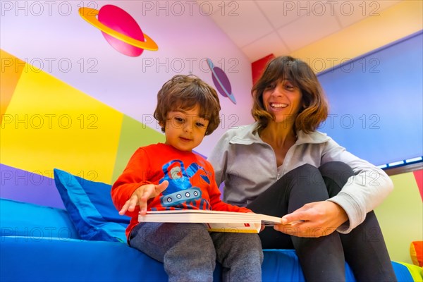 Woman teacher playing with a child reading a book and having fun