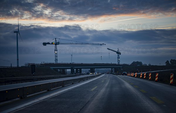 Cranes stand at a bridge construction site on the A10 motorway at the Pankow interchange at dawn. Berlin