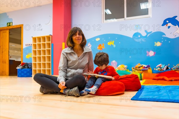 Portrait of a female teacher with a child sitting reading a story book