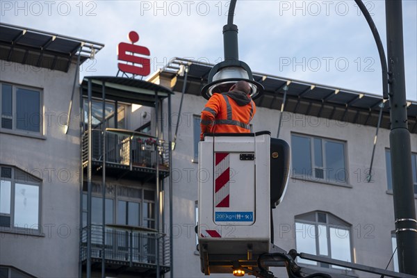 Man in high-visibility waistcoat repairing street lamp