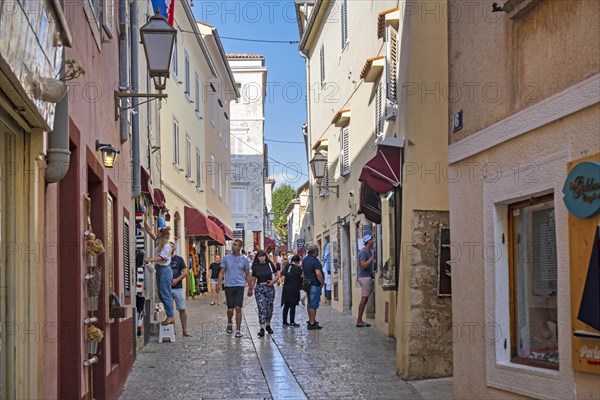 Tourists walking in alley with shops in the historic Old Town of Krk