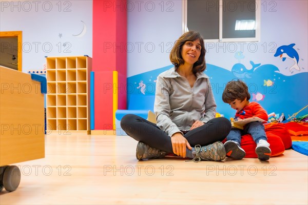 Portrait of a female teacher with a child sitting reading a story book