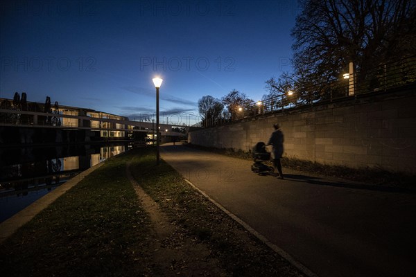 A woman with a pram stands out on the Spreebogen at blue hour