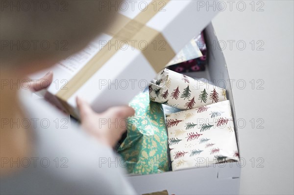 Symbolic photo on the subject of sending Christmas presents by post. A woman opens a parcel with Christmas presents. Berlin