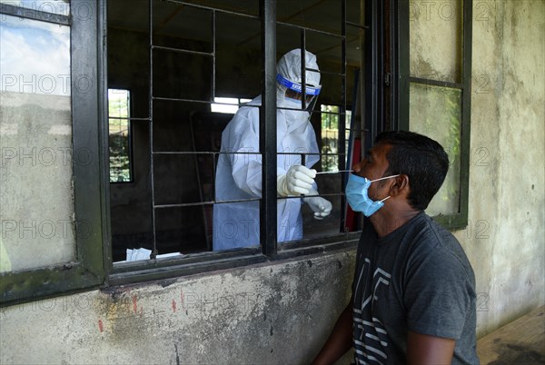 Health worker collects swab sample to test for COVID-19 coronavirus disease during a vaccination drive on the outskirt of Guwahati in India on Monday