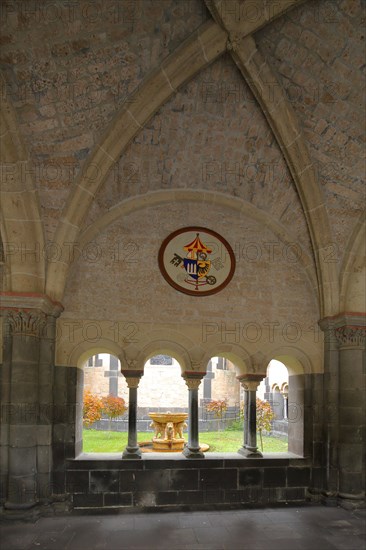 Papal coats of arms in the cloister and view of inner courtyard with lion fountain