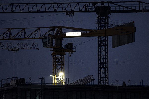 A worker draws on scaffolding and in front of a crane on a newly built house