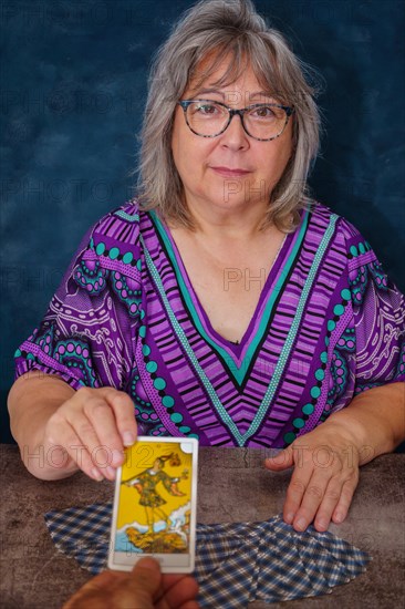 Elderly woman fortune teller handing a man the tarot card of the madman