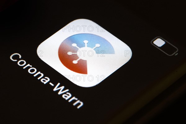 The Corona warning app is displayed on the screen of a smartphone. The app is designed to help trace and interrupt chains of infection of SARS-CoV-2