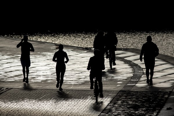 People stand out on the banks of the Spree in Berlin