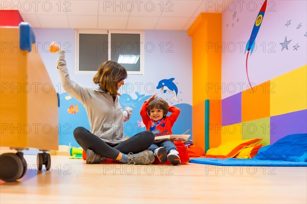 Woman teacher with a child sitting reading a book and expressing things from the story