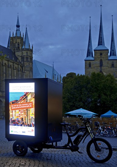 Illuminated advertising on cargo bike on the cathedral square in the evening