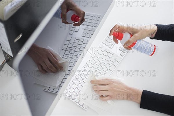 Hygiene at the workplace. A woman disinfects the keyboard at her workplace with disinfectant spray. Berlin