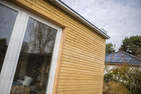 Symbolic photo on the subject of building with wood. The extension of a house is clad in larch wood. Berlin