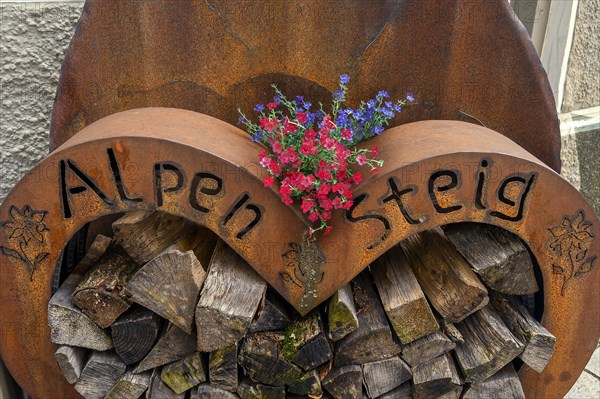 Iron storage container with firewood and geraniums