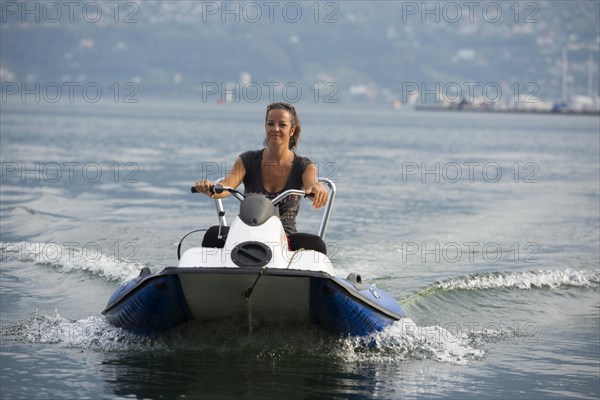 Happy woman driving a boat on the water