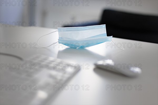 Mask at the workplace. A mask lies on a desk next to the keyboard and mouse. Berlin