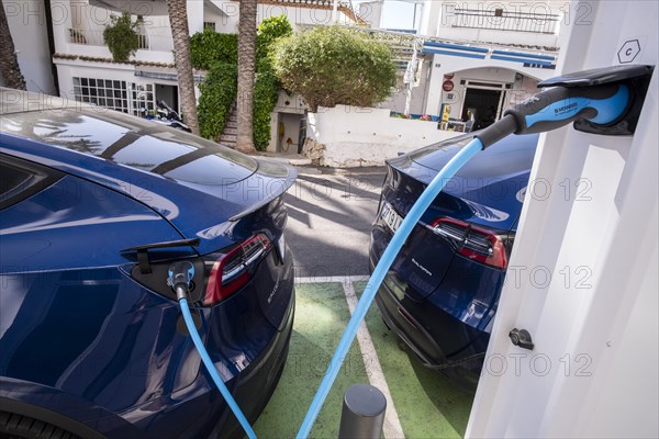 Two Tesla electric vehicles charging at a charging station in the village of Altea La Vella