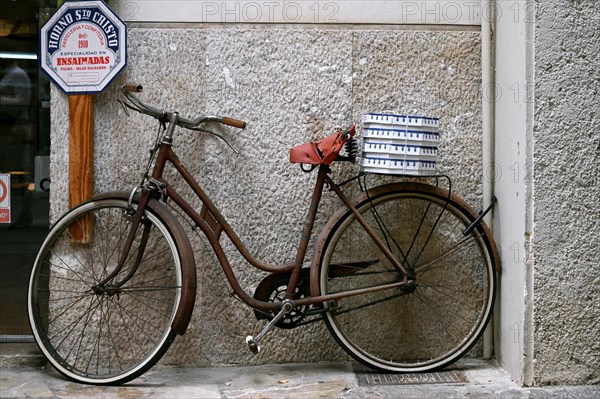Old bicycle with ensaimada packages on the rack in front of a bakery