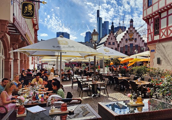 People in the outdoor restaurant at the Roemerberg with the town hall and the Commerzbank