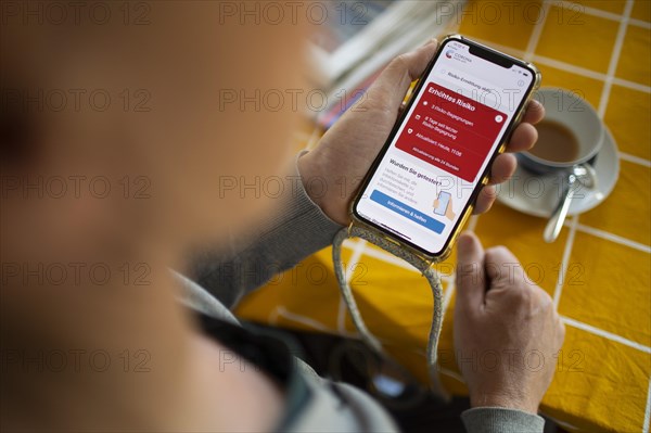Corona Warnapp. Person looks at the Corona Warnapp indicating 3 risk encounters.