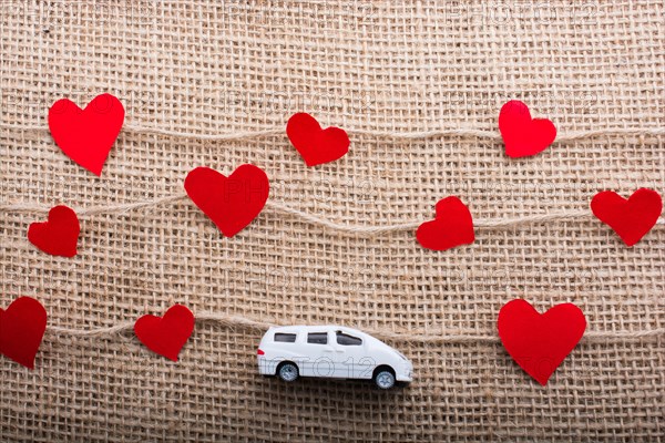 Love concept with car and paper heart on linen threads