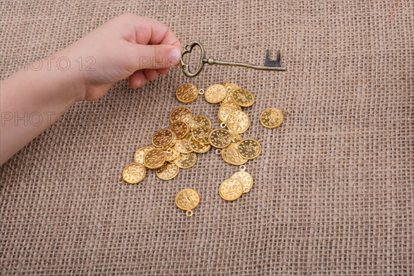 Hand holding a retro styled key over fake gold coins