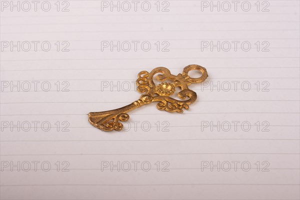 Golden color decorative key on lined sheet of paper