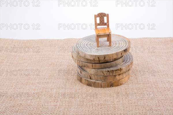 Brown color wooden toy chair on wooden logs on canvas
