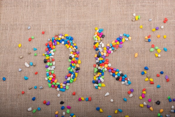 Colorful pebbles form the word OK on canvas ground