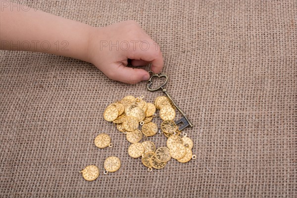 Hand holding a retro styled key over fake gold coins