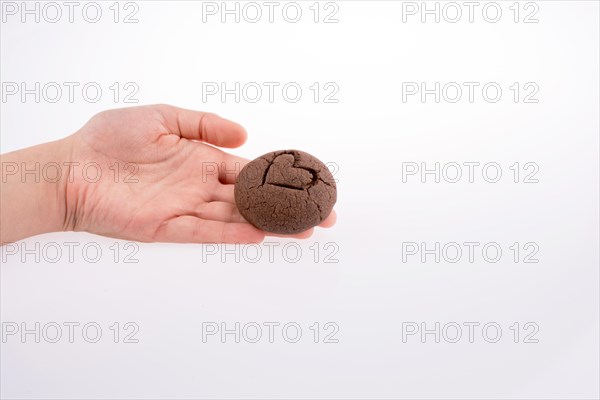 Hand holding a heart patterned chocolate cookie on a white background