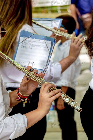 Woman's hands playing a transverse flute with sheet music in the background