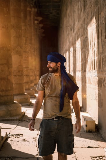 Young man in blue turban walking on the columns of the Edfu Temple near the city of Aswan. Egypt