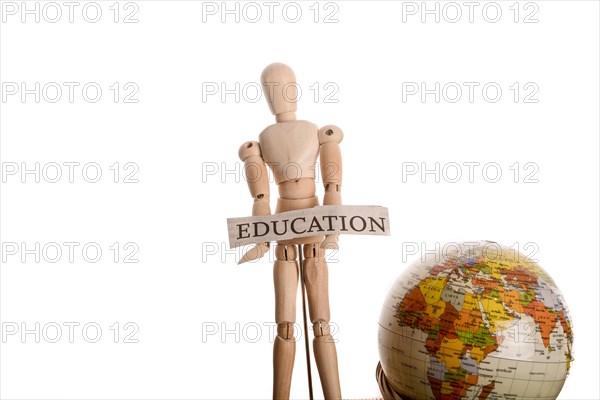 Wooden man holding education sign standing in front of a globe on a white background