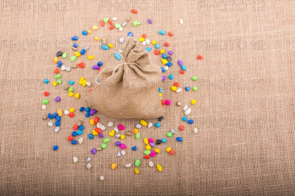 Little sack amid colorful pebbles spread on canvas