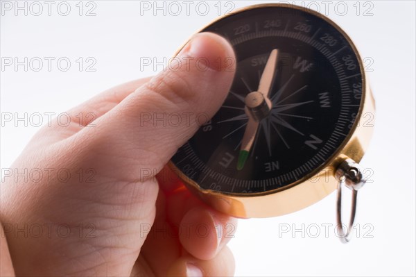 Hand holding a compass on a white background