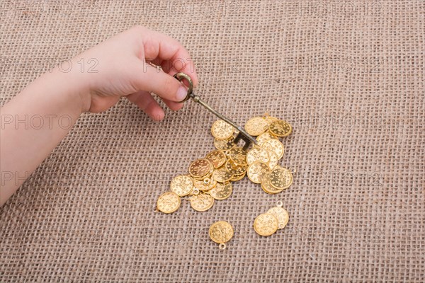 Hand holding a retro styled key over fake gold coins