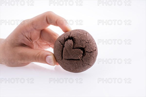 Hand holding a heart patterned chocolate cookie on a white background
