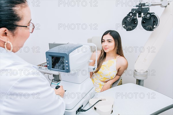 Woman patient having consultation with optometrist in office. Optometrist with female patient in the autorefractor