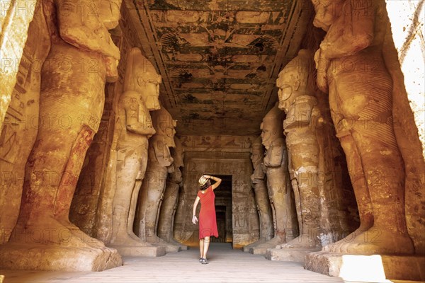 A young woman in a red dress at the Abu Simbel Temple next to the sculptures