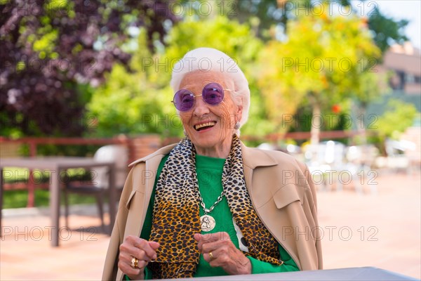 An elderly woman dancing in the garden of a nursing home or retirement home at a summer party wearing sunglasses