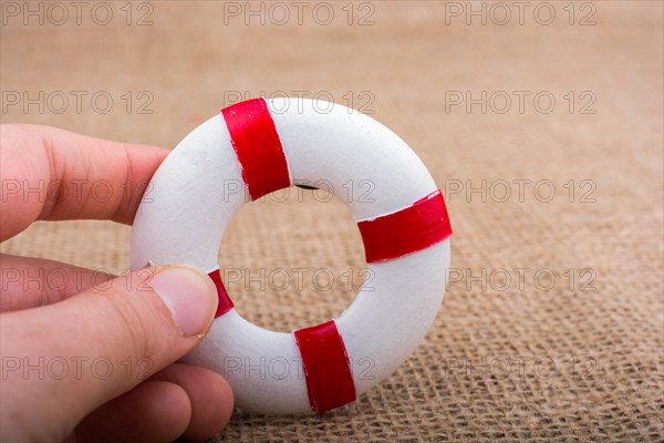 Hand holding a Lifesaver or life preserver on a fabric background