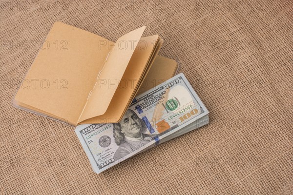 Notebook placed beside bundle of US dollar banknotes