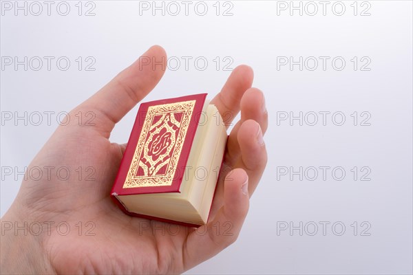 Hand holding The Holy Quran on a white background