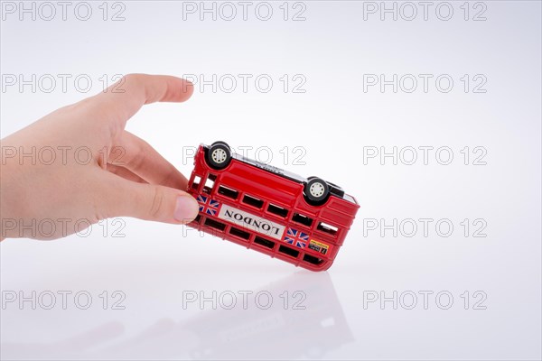 Child hand playing with London double decker bus model on white background