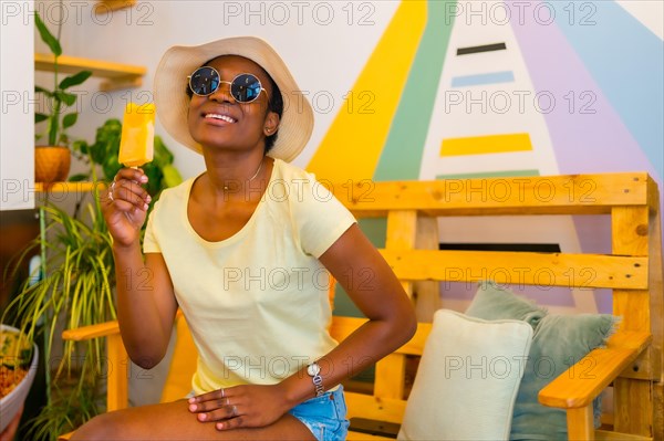 Portrait of black African ethnicity woman eating a mango ice cream in a shop